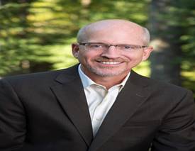 A person wearing a suit and tie smiling at the camera

Description automatically generated